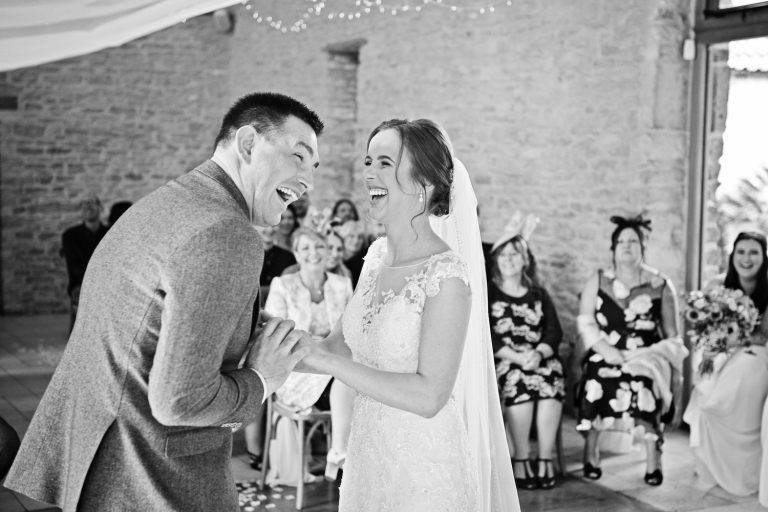 Bride and groom laughing during their wedding ceremony at Kingscote Barn.