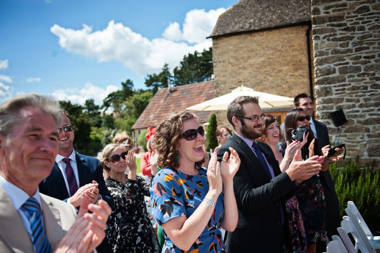 Documentary photo of wedding guest clapping the bride and groom after their wedding ceremony.