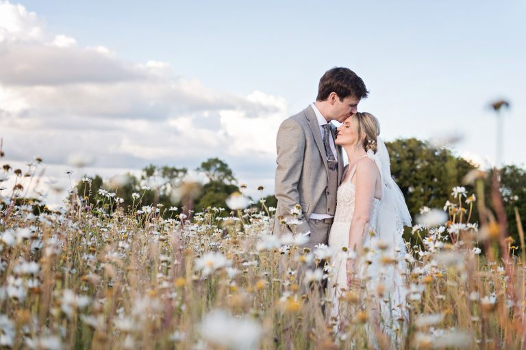 Bride and groom grab a moment together in the wild flower fields at Kingscote Barn.