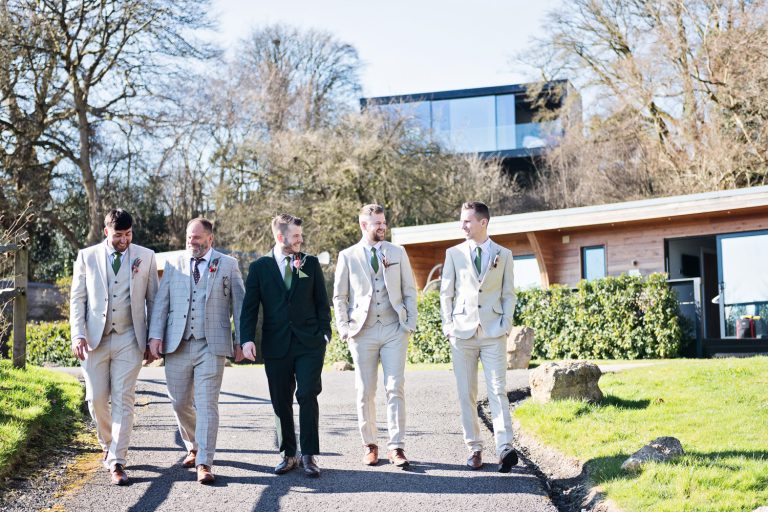 Groomsmen walk towards wedding at Kingscote Barn.