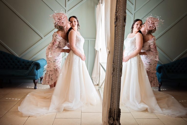 Mother of the bride kisses her daughter. Candid photo but with reflection of mirror.