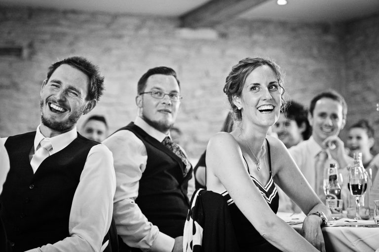 Candid photo of wedding guests laughing during wedding speeches.