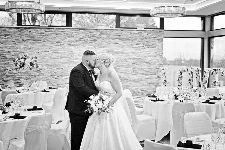 Candid b&W pic of bride and groom kissing in the Cotswold Suite at Tewkesbury Park.