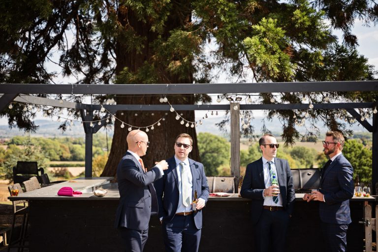 Story telling image of wedding guests chatting in front of the outside kitchen at Tewkesbury Park