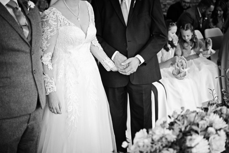 Candid moment of father of the bride holding the brides hand whilst getting married at Tewkesbury Park