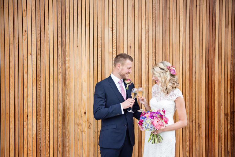 Bride and groom celebrate with a glass of fizz at their wedding at Tewkesbury Park.