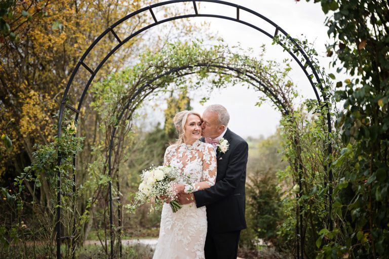 Bride and groom kiss in the gorgeous gardens at Tewkesbury Park.