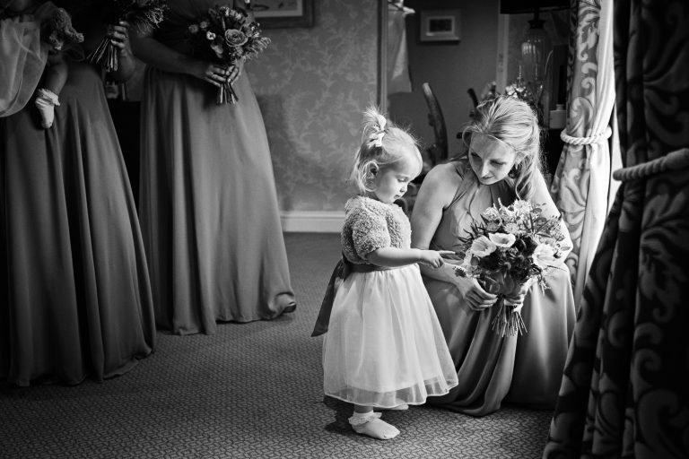 B&W documentary photo of bridesmaid pointing at flowers.